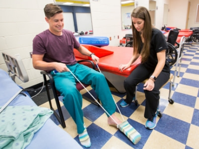 A student learns how to use a sock aid to increase a patient's independence